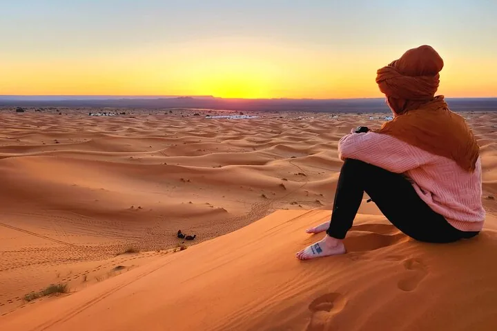 A person sitting on a dune watching the sunrise over Erg Chebbi