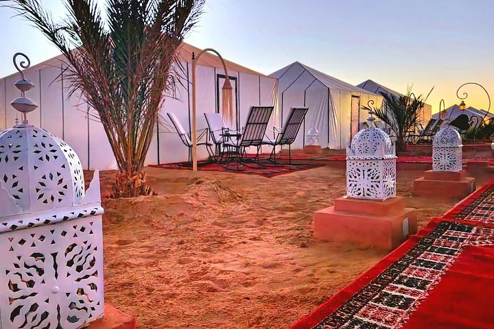 White tents and lanterns in a luxury desert camp at sunset