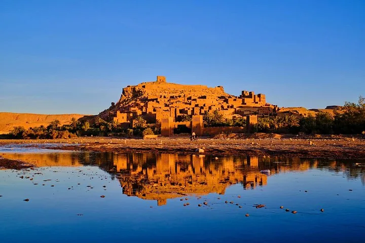 Ait Benhaddou reflected in the river water under warm sunset light
